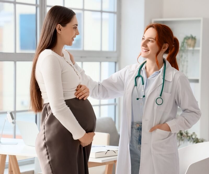Female,Doctor,Talking,To,Pregnant,Woman,In,Clinic